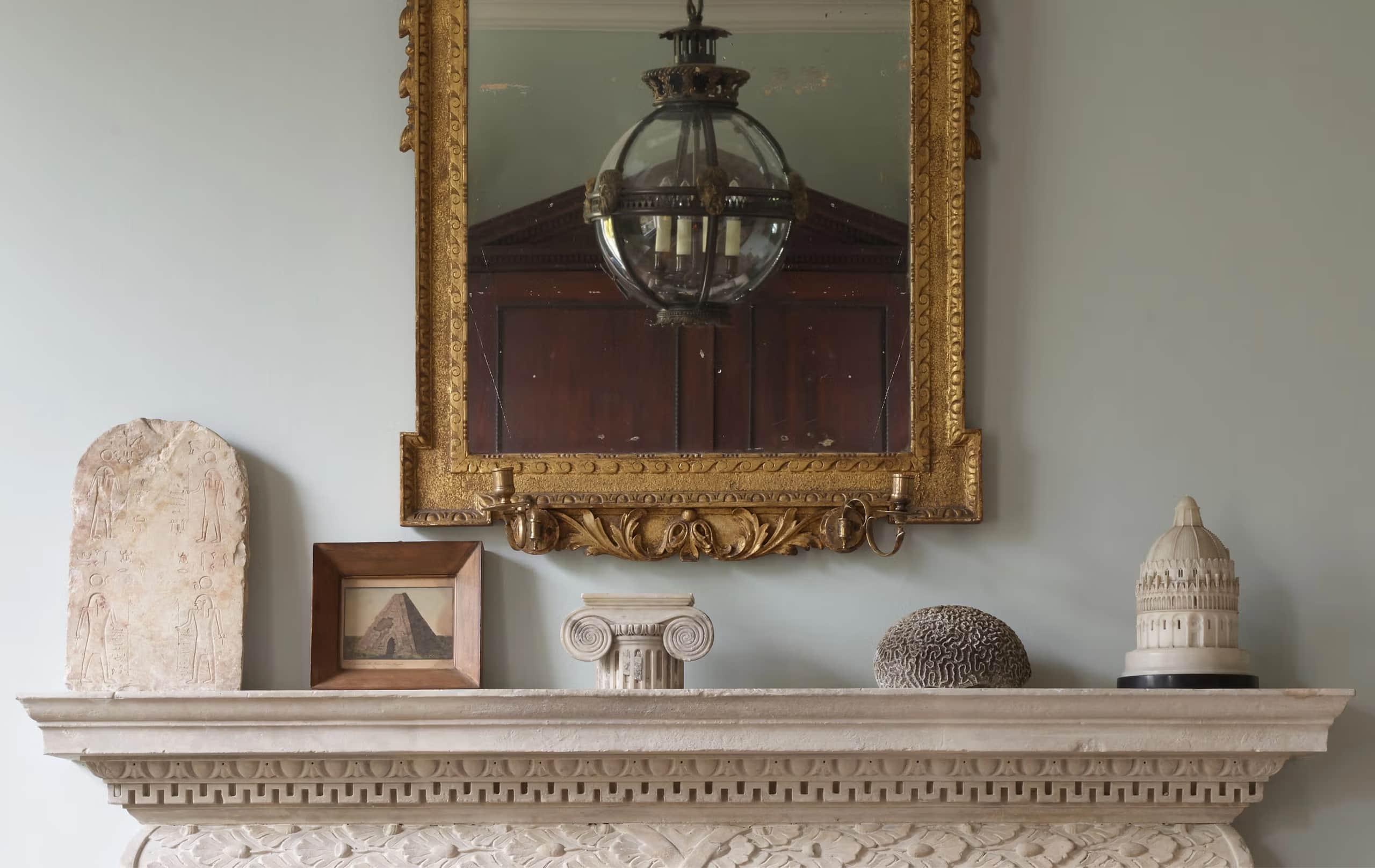 Jamb mantelpiece with gilded mirror, hanging lantern, and antiques