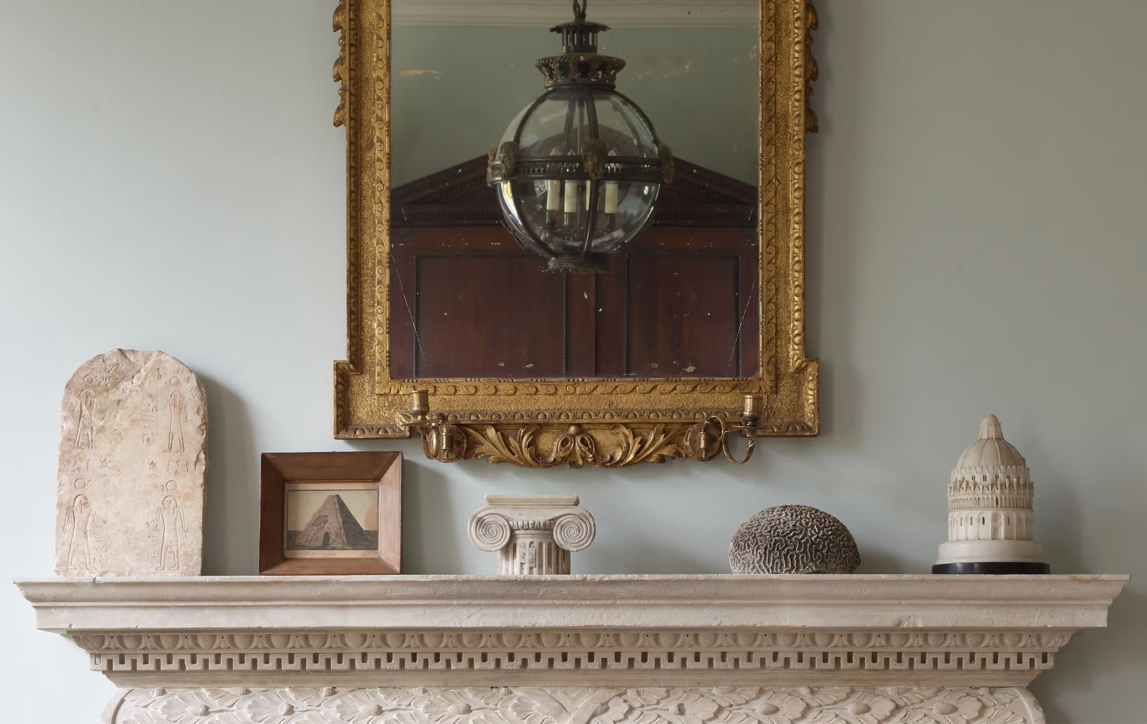 Jamb mantelpiece with gilded mirror, hanging lantern, and antiques
